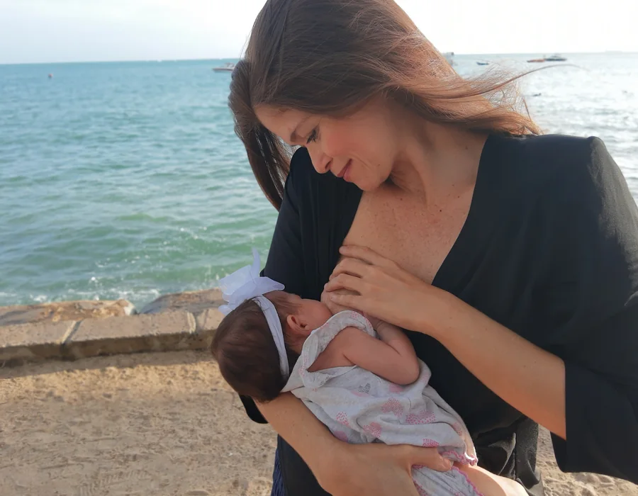 Mãe amamentando a recém-nascida perto de uma janela